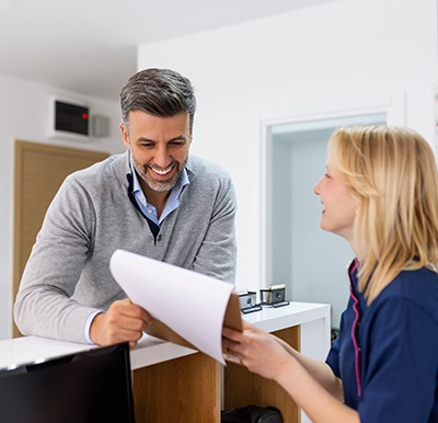 Patient and dental team member talking at front desk