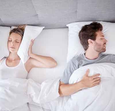 Man snoring while his wife covers her ears