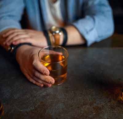 Man sitting at table, drinking liquor