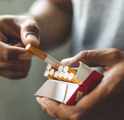 Man pulling cigarette from pack, preparing to smoke