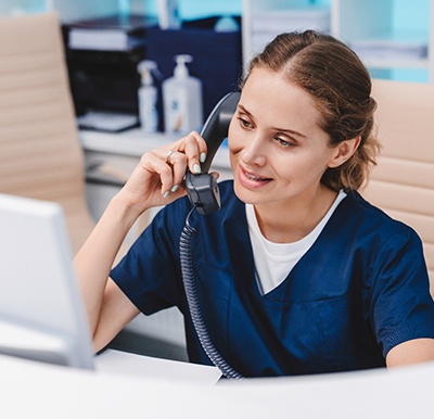 a front desk worker talking on the phone with a dental patient