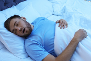 Man in blue shirt snoring in bed